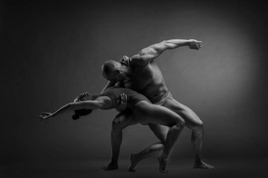 Siyah-beyaz bir çift dansçının zarif bir akrobatik poz içinde koyu bir arka planda çekilmiş bir fotoğrafı..