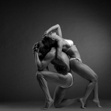 Siyah-beyaz bir çift dansçının zarif bir akrobatik poz içinde koyu bir arka planda çekilmiş bir fotoğrafı..