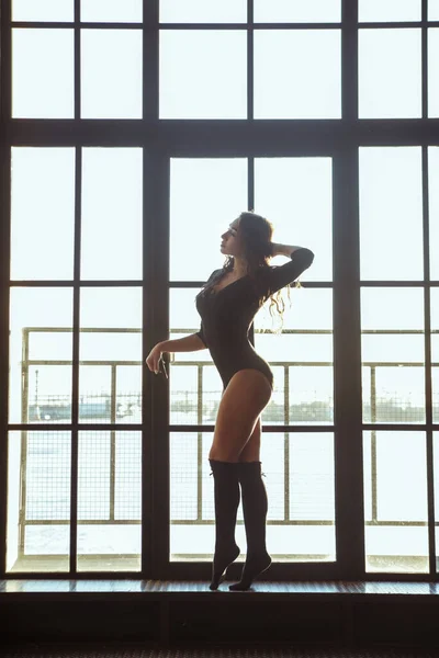 一个身材苗条的女运动员在一个大窗户的背景下的轮廓 — 图库照片