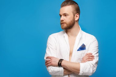 Mavi arka planda beyaz keten ceketli, sakallı, zarif bir adam..