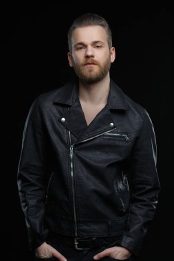 Siyah deri ceketli sevimli sakallı adam siyah arka planda izole edilmiş..