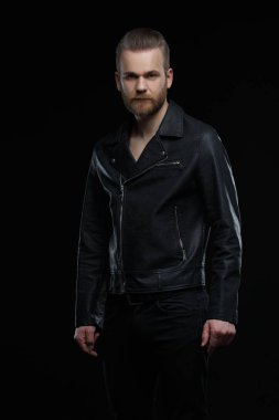 Siyah deri ceketli sevimli sakallı adam siyah arka planda izole edilmiş..