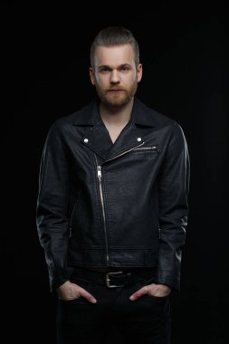 Siyah deri ceketli sevimli sakallı adam siyah arka planda izole edilmiş..