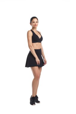 Siyah eşofmanlı, ince atletik bir kız, beyaz arka planda izole bir etek giyiyor..