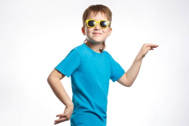 Mavi elbiseli ve güneş gözlüklü küçük çocuk mutlu bir şekilde dans ediyor..