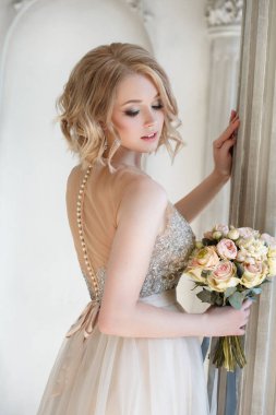 Şık bir elbise giymiş, elinde düğün buketi olan zarif bir sarışın gelin portresi..