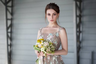 Şık bir elbise giymiş, elinde buketi olan zarif bir gelinin portresi..