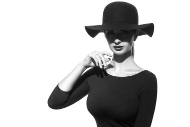 Gözlerinin önünde gölgesi olan geniş kenarlı şapkalı bir kız siluetinin siyah ve beyaz moda portresi..