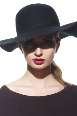 Geniş kenarlı şapkalı, gözlerinin önünde gölgesi olan bir kızın siluetinin moda portresi..