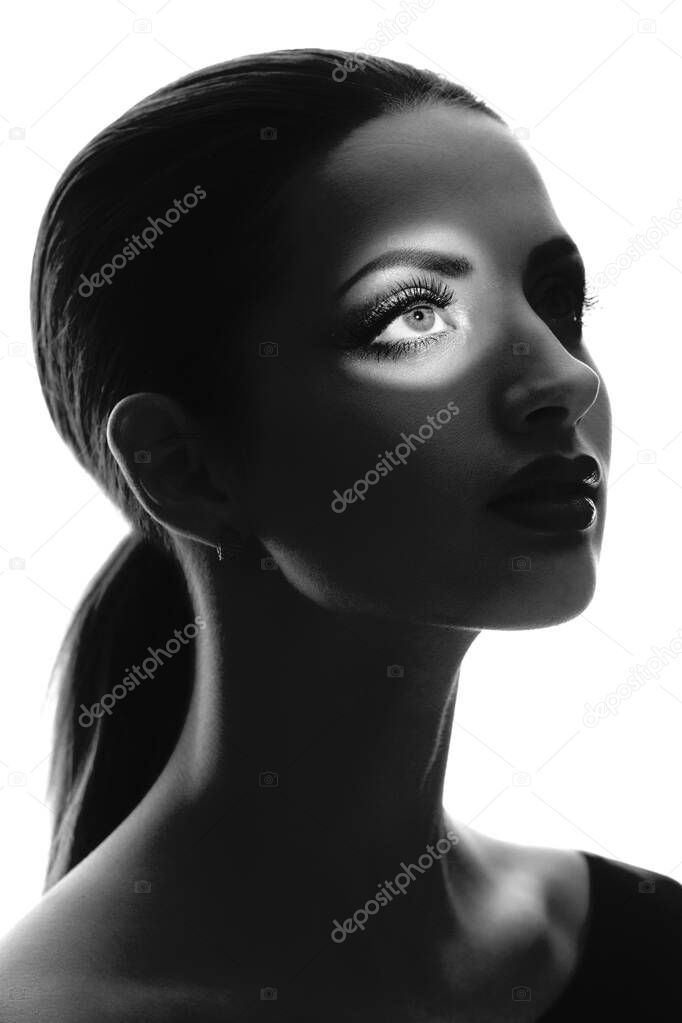 Black and white mysterious silhouette portrait of elegant girl with light focus on eye isolated on white background.