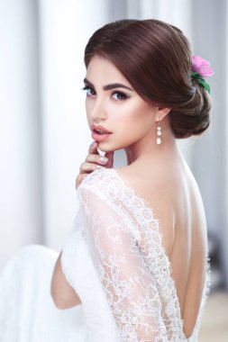 Sırtı açık, dantel elbiseli güzel bir esmer gelin portresi.