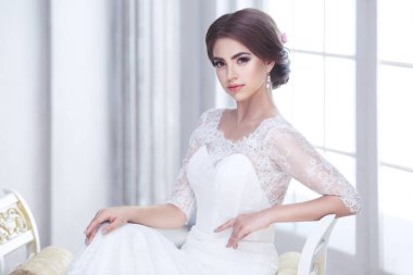 Zarif esmer gelin koridorda kolonlarla oturuyor.