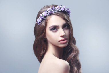 Gri bir arka planda yalıtılmış leylak çiçekli güzel bir kızın taze bahar portresi..