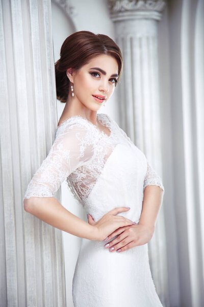 Portrait of an elegant brunette bride is in a luxury hall with columns