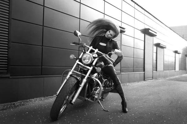 Şehir caddesinde motosikletli güzel, narin bir kızın siyah beyaz fotoğrafı..