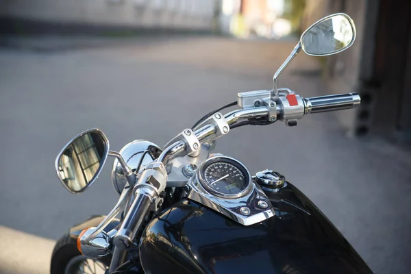 Motorcycle steering wheel and dashboard on the street.