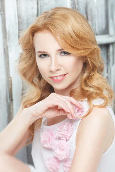 Eski duvarın arka planında bukleleri olan gülümseyen bir sarışının nazik portresi