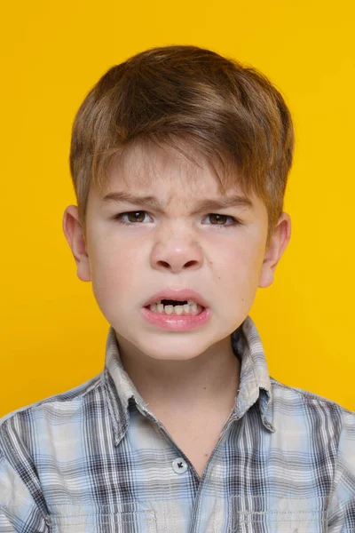 穿着格子呢衬衫的可爱小男孩 情绪化地咧嘴笑着 露出被黄色背景隔开的牙齿 — 图库照片
