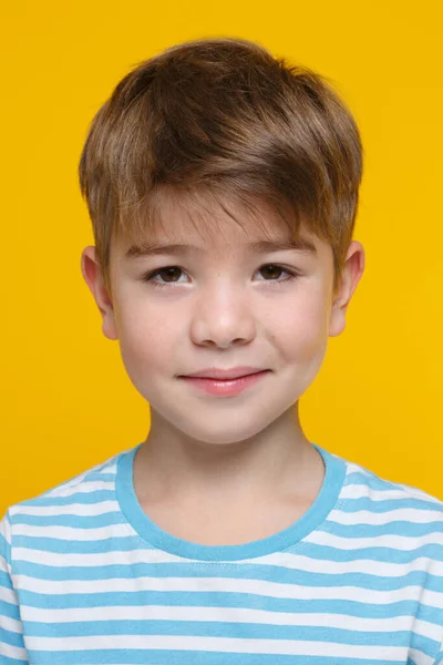 一个穿着白兰色条纹衣服的可爱小男孩的画像 他在明亮的橙色背景下孤独地微笑着 — 图库照片