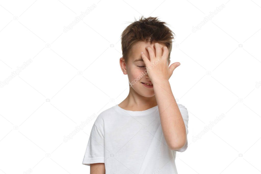 Little boy in a white T-shirt raised a palm to his forehead Isolated on a white background.