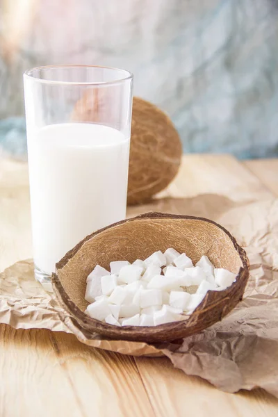 Kokos schijfjes en een glas melk. Kokos op een houten tafel. VEG — Stockfoto