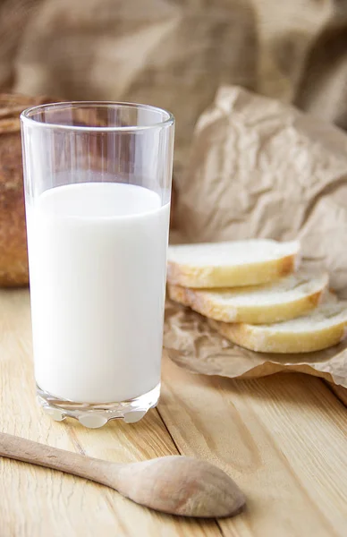 นมแก้วกับขนมปังบนโต๊ะไม้ ขนมปังสีน้ําตาล — ภาพถ่ายสต็อก