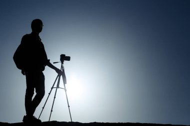 Bir fotoğrafçı ile güneş ve mavi gökyüzü ile tripod