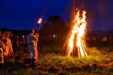 Bolshaya Rechka, Rusya - 24 Haziran 2017: Angara Nehri yakınlarındaki Beyaz Rusya tatiliivan Kupala'yı kutlamak için krivichi nehri, ulusal kostümlü bir çift sembolik ateşi yakıyor