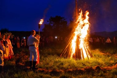 Bolshaya Rechka, Rusya - 24 Haziran 2017: Angara Nehri yakınlarındaki Beyaz Rusya tatiliivan Kupala'yı kutlamak için krivichi nehri, ulusal kostümlü bir çift sembolik ateşi yakıyor