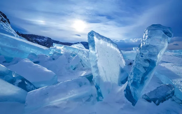 Blöcke von gebrochenem blauem Eis auf Himmelshintergrund mit Sonne und Wolken lizenzfreie Stockbilder