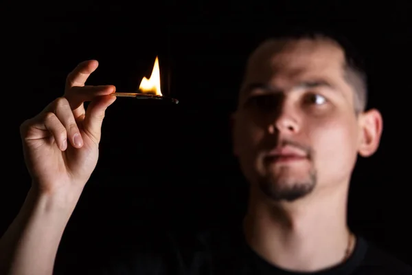 Драматический темный портрет человека и зажженный спичечный огонь на черном фоне — стоковое фото