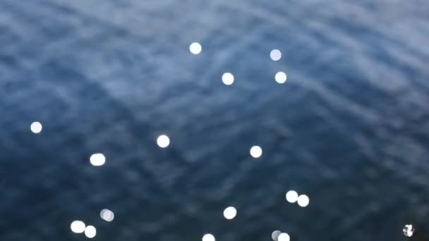 Bokeh napfény tükröződik a víz felszínén. Absztrakt elmosódott fókuszon kívül bokeh háttér képek — Stock videók