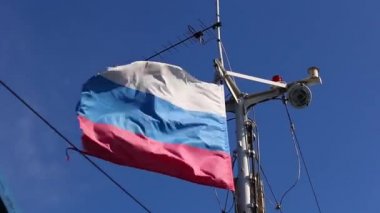 Uzun yelkenli Rus gemisi. Rüzgarda dalgalanan bayrak. Boğuk güneşle aydınlatılıyor..