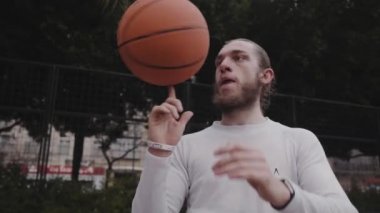 Basketbolcu adam topu ağır çekimde döndürüyor.