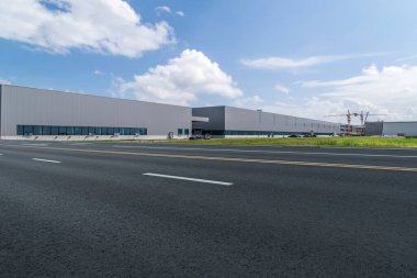 Yol asfaltı kaldırımı ve modern fabrika deposu.