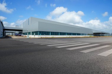 Yol asfaltı kaldırımı ve modern fabrika deposu.