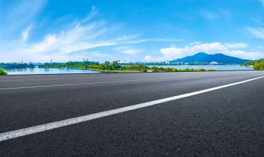 Boş asfalt yol meydanı ve mavi çizgilerin altında doğal manzara.