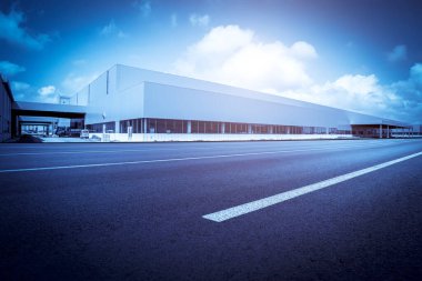 Yol asfaltı kaldırımı ve modern fabrika deposu.