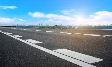 Boş asfalt yol meydanı ve mavi çizgilerin altında doğal manzara.