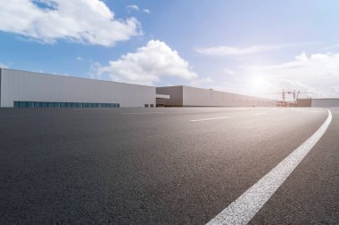 Yol asfaltı kaldırımı ve modern fabrika deposu.
