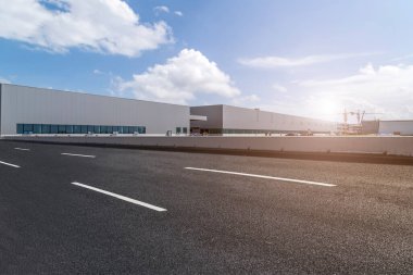 Yol asfaltı kaldırımı ve modern fabrika deposu.