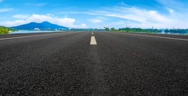 Boş asfalt yol meydanı ve mavi çizgilerin altında doğal manzara.