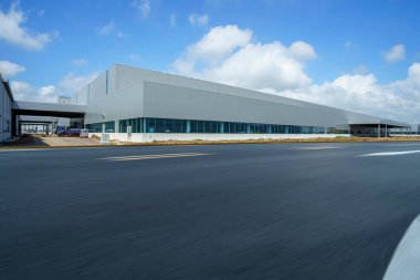 Yol asfaltı kaldırımı ve modern fabrika deposu.
