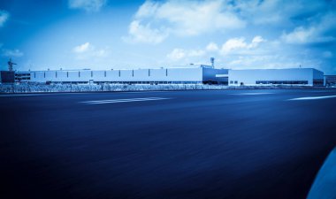 Yol asfaltı kaldırımı ve modern fabrika deposu.