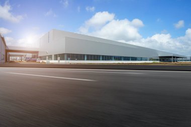 Yol asfaltı kaldırımı ve modern fabrika deposu.