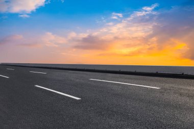 Boş asfalt yol ve batan güneşte doğal manzara