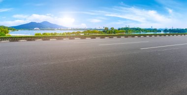 Boş asfalt yol meydanı ve mavi çizgilerin altında doğal manzara.