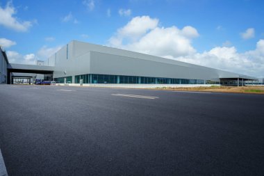 Yol asfaltı kaldırımı ve modern fabrika deposu.