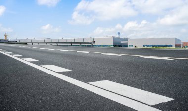 Yol asfaltı kaldırımı ve modern fabrika deposu.