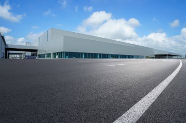 Yol asfaltı kaldırımı ve modern fabrika deposu.